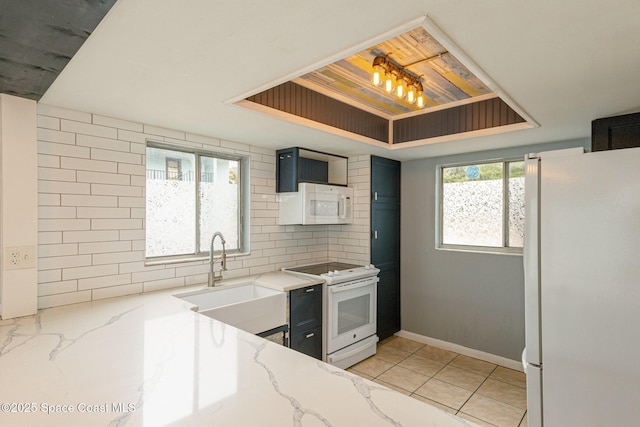 kitchen with white appliances, light stone countertops, sink, and decorative backsplash