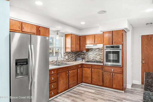 kitchen with appliances with stainless steel finishes, sink, light hardwood / wood-style flooring, and backsplash