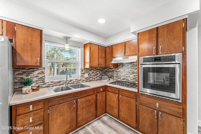 kitchen with sink, backsplash, stainless steel appliances, and hanging light fixtures