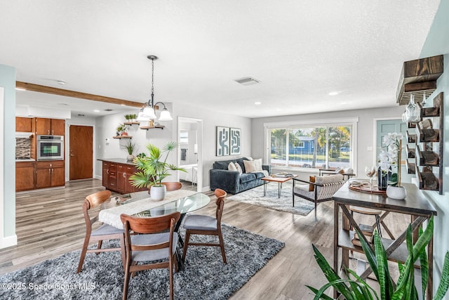 dining area with a textured ceiling and light hardwood / wood-style floors