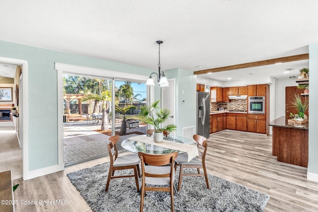 dining room with beamed ceiling, an inviting chandelier, and light hardwood / wood-style flooring