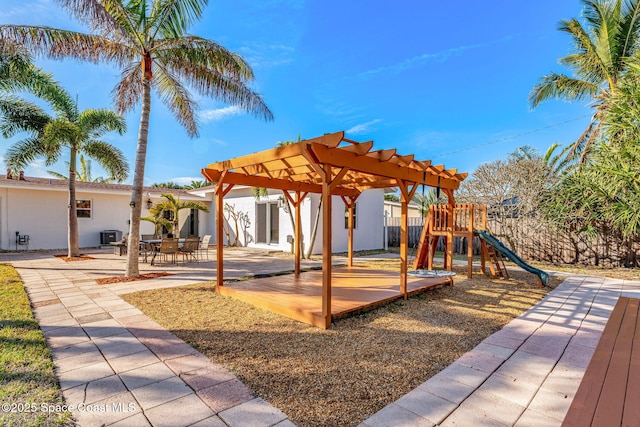 view of jungle gym featuring central AC unit, a pergola, and a patio area