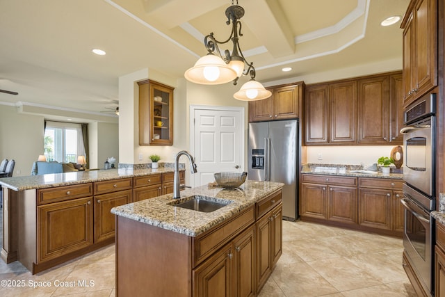 kitchen featuring a kitchen island with sink, a sink, appliances with stainless steel finishes, brown cabinetry, and glass insert cabinets