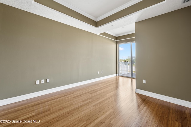 empty room featuring light wood finished floors, visible vents, baseboards, and crown molding