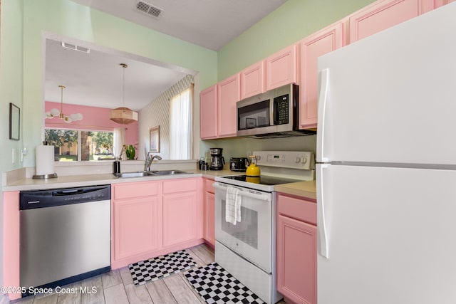 kitchen featuring appliances with stainless steel finishes, hanging light fixtures, a notable chandelier, and sink