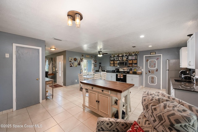 kitchen featuring stainless steel appliances, a kitchen island, white cabinets, ceiling fan, and sink