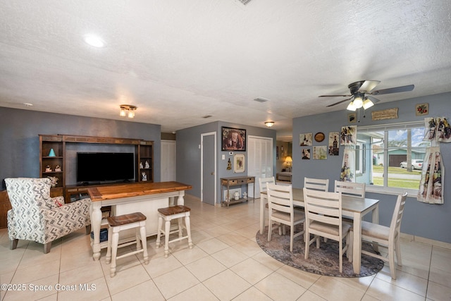 tiled dining area with a textured ceiling and ceiling fan