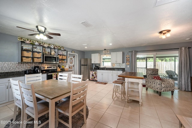 tiled dining area featuring a textured ceiling, ceiling fan, and sink