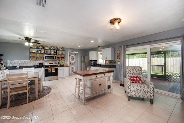 kitchen with stainless steel appliances, white cabinets, decorative backsplash, and a textured ceiling