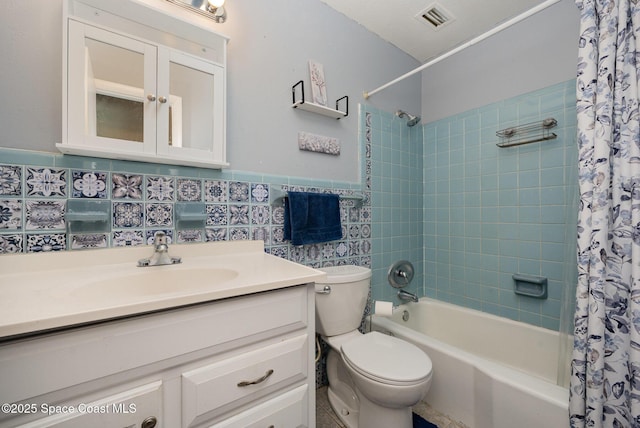 full bathroom with tile walls, shower / bath combination with curtain, vanity, and toilet