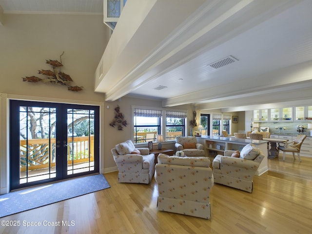 living room featuring beam ceiling, crown molding, french doors, and light wood-type flooring