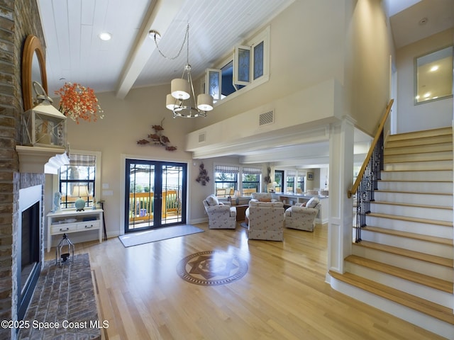 living room with beam ceiling, french doors, light hardwood / wood-style flooring, and a brick fireplace