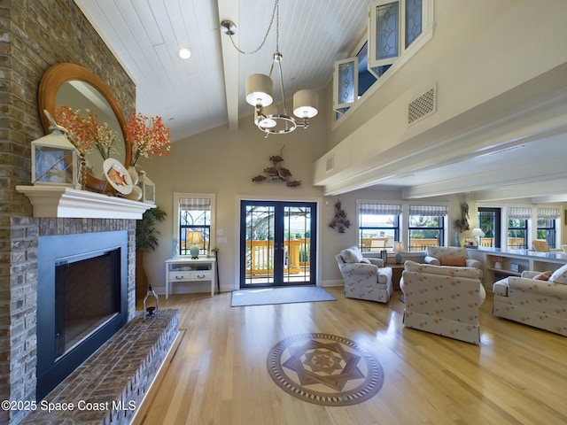 living room with wooden ceiling, an inviting chandelier, french doors, light hardwood / wood-style flooring, and a brick fireplace