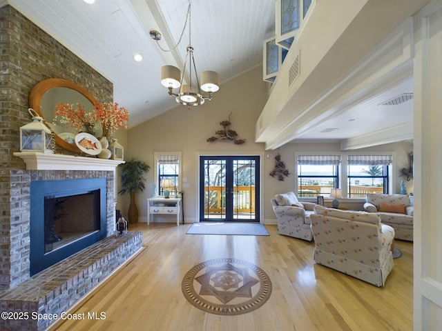 living room with a fireplace, hardwood / wood-style floors, french doors, and a notable chandelier