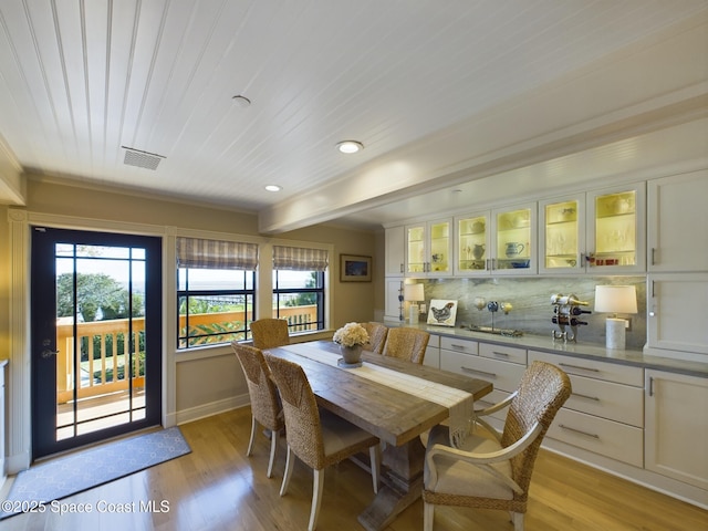 dining room featuring beamed ceiling and light hardwood / wood-style flooring