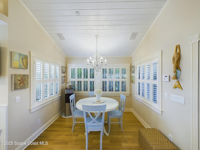 dining space with a chandelier, hardwood / wood-style flooring, and vaulted ceiling