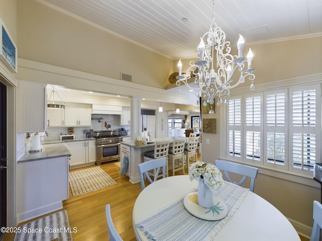 dining area with an inviting chandelier, light wood-type flooring, and ornamental molding