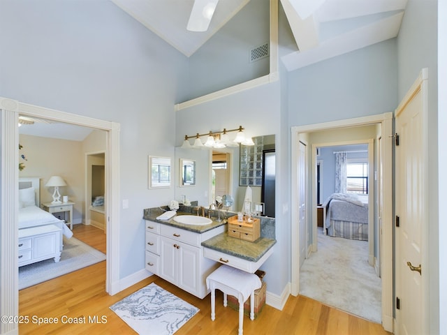 bathroom with wood-type flooring, vanity, and high vaulted ceiling