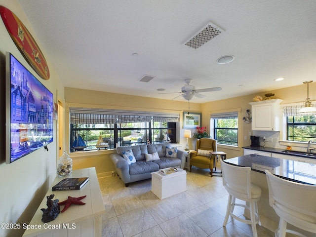 tiled living room with ceiling fan and sink