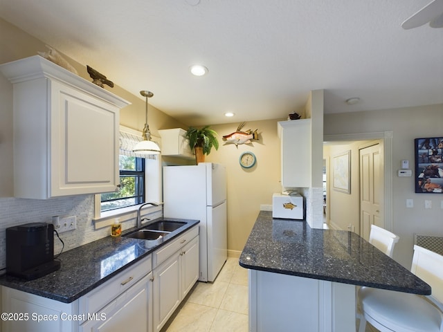 kitchen featuring sink, white cabinets, white fridge, and light tile patterned floors