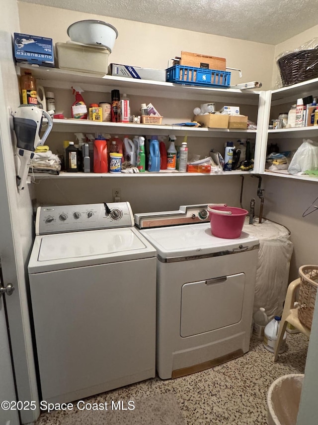 laundry room featuring washer and clothes dryer and a textured ceiling