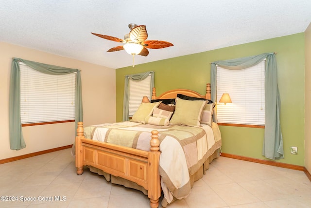 bedroom featuring ceiling fan, light tile patterned floors, and a textured ceiling