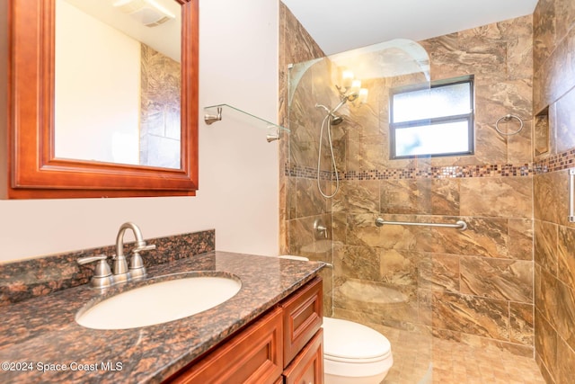 bathroom featuring a tile shower, vanity, and toilet