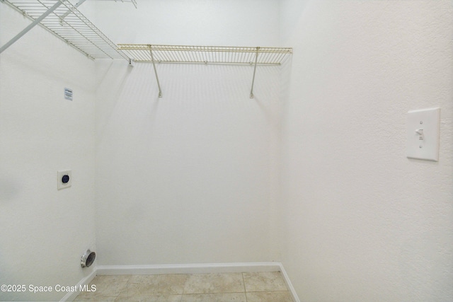 clothes washing area featuring electric dryer hookup and light tile patterned flooring