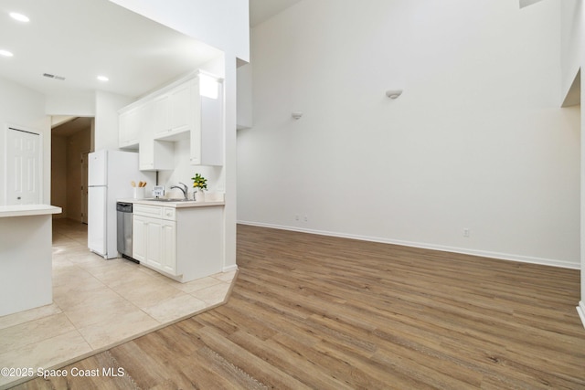 kitchen with light wood-type flooring, white cabinetry, stainless steel dishwasher, and sink