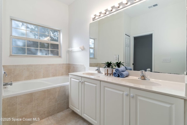 bathroom with tiled bath, tile patterned flooring, and vanity