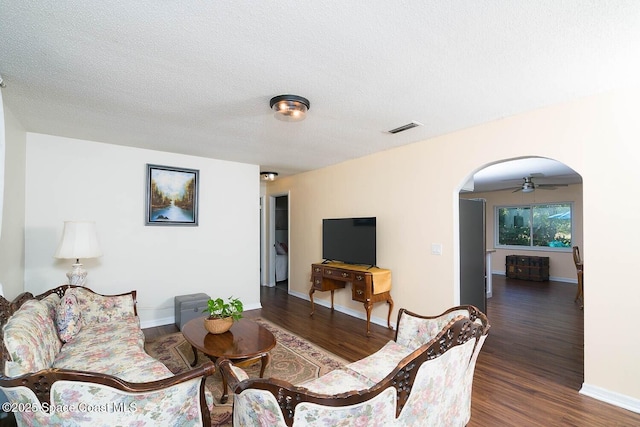 living room featuring a textured ceiling, dark hardwood / wood-style flooring, and ceiling fan