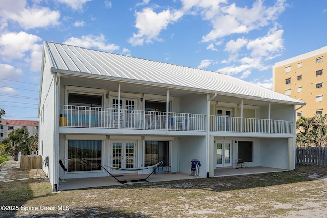 rear view of house with french doors, a balcony, and a patio area