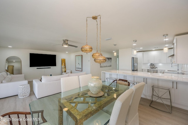 dining space with ceiling fan, sink, and light hardwood / wood-style flooring