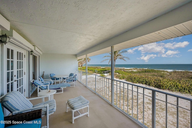 balcony with a water view and a view of the beach