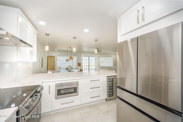 kitchen with wine cooler, light stone counters, decorative light fixtures, appliances with stainless steel finishes, and kitchen peninsula