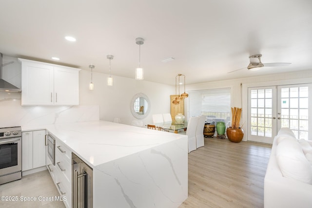 kitchen featuring tasteful backsplash, decorative light fixtures, kitchen peninsula, stainless steel appliances, and white cabinets