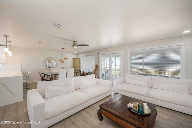 living room with french doors, ceiling fan, and light wood-type flooring