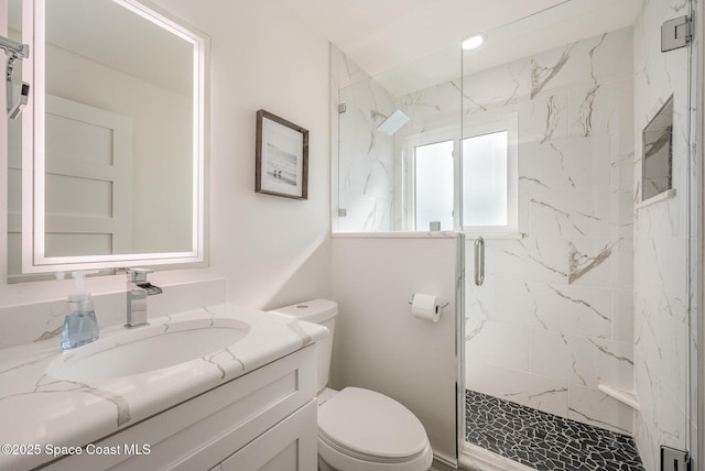 bathroom featuring vanity, a shower with shower door, and toilet