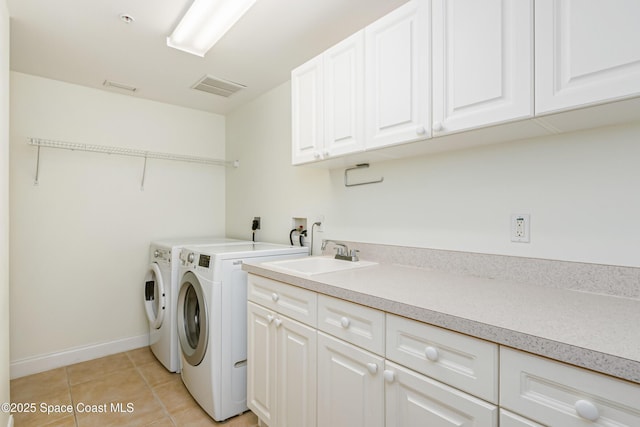 clothes washing area featuring sink, washing machine and clothes dryer, light tile patterned floors, and cabinets