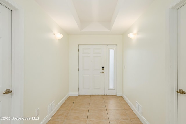 entrance foyer with light tile patterned flooring and a tray ceiling