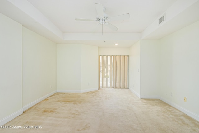 carpeted empty room featuring a tray ceiling and ceiling fan