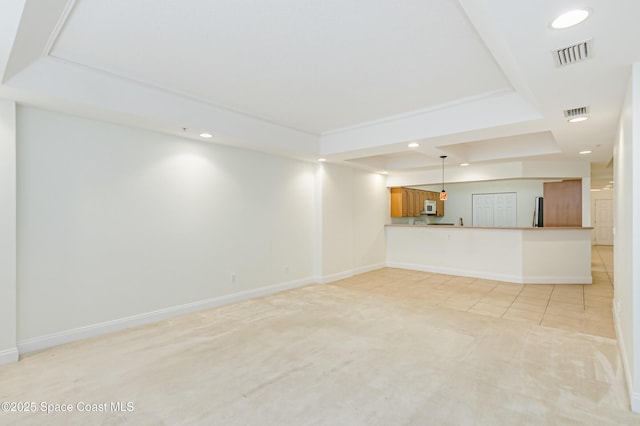 unfurnished living room featuring light carpet and a tray ceiling