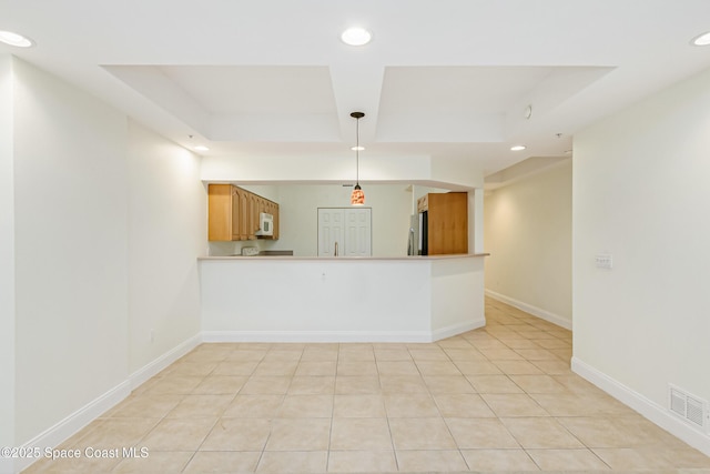 kitchen with decorative light fixtures, light tile patterned flooring, stainless steel fridge, and a raised ceiling