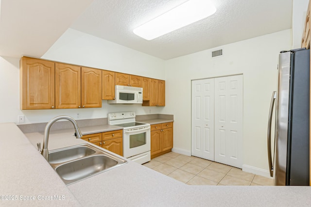 kitchen with sink, light tile patterned flooring, white appliances, and a textured ceiling