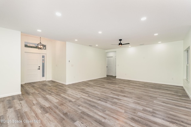 interior space featuring ceiling fan with notable chandelier and light hardwood / wood-style flooring