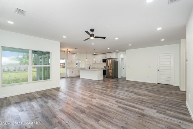 unfurnished living room featuring hardwood / wood-style flooring, ceiling fan, and sink