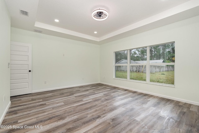 unfurnished room with a tray ceiling, wood-type flooring, and a textured ceiling