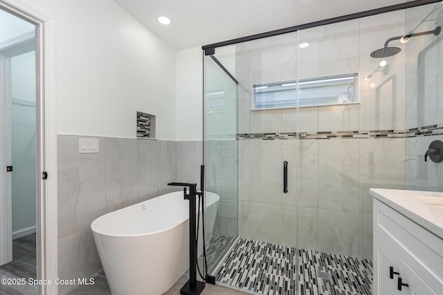 bathroom featuring vanity, shower with separate bathtub, and tile walls