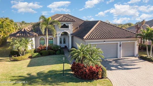 mediterranean / spanish home featuring a front lawn and a garage