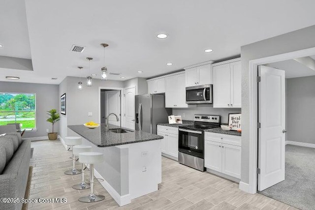 kitchen featuring white cabinetry, a kitchen island with sink, sink, and stainless steel appliances